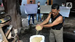 Perajin menunjukkan kedelai saat aksi mogok produksi di Sentra Produksi Tempe Kelurahan Tugu, Cimanggis, Depok, Senin (21/02/2022).  Harga kedelai impor yang mencapai Rp1,1 juta/kwintal membuat ratusan perajin tahu-tempe di Jabodetabek mogok produksi tiga hari ke depan. (merdeka.com/Arie Basuki)