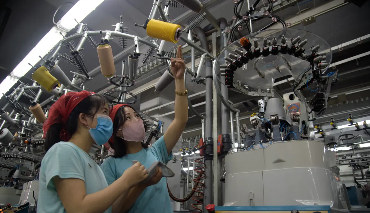 Dua pekerja wanita mengecek benang saat berada di jalur produksi yang membuat kaus kaki pria di Pabrik Kaus Kaki Pyongyang di Korea Utara (24/5/2021). Pekerja Pabrik Kaus Kaki Pyongyang telah memproduksi berbagai kaus kaki berkualitas tinggi. (AFP/Kim Won Jin)