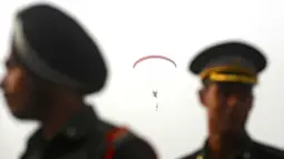 Aksi seorang anggota tentara India dari tim display paramotor PRTC saat terjun payung selama latihan gabungan di akademi pelatihan perwira di Chennai (9/3). (AFP Photo/Arun Sankar)