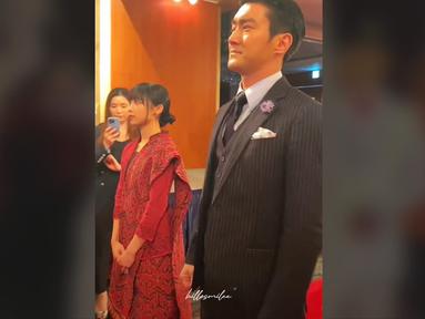 Potret Choi Siwon saat jalan berdampingan dengan Dita memasuki area acara. Keduanya mengenakan busana formal dan sesekali tampak tersenyum. Sementara para tamu undangan tampak sibuk mendokumentasikan momen ini. (Foto: TikTok/ hillosmilee)