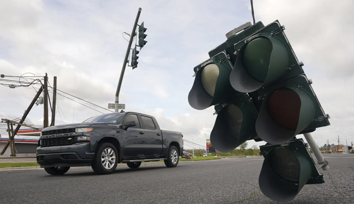 Kendaraan melintasi lampu lalu lintas yang tergantung di kabel setelah terjangan Badai Ida di LaPlace, Louisiana, Senin (30/8/2021). Badai Ida ini sebagai salah satu badai paling kuat yang pernah melanda Amerika Serikat. (AP Photo/Steve Helber)