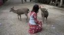 Seorang turis membelai rusa yang ada di taman Nara, kota Nara, Jepang pada 7 Desember 2018. Taman Nara yang memiliki luas 600 hektare ini, menjadi tempat tinggal bagi lebih dari 1.000 ekor rusa liar. (Behrouz MEHRI / AFP)
