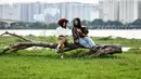 Para gadis berbagi momen ringan sambil berpose untuk berfoto di lapangan terbuka di sepanjang tepi sungai Merah di Hanoi (13/0/2020). (AFP/Manan Vatsyayana)