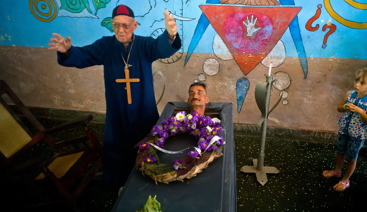 Marcelino Rogelio Estrada yang berperan sebagai imam melakukan ritualnya saat festival Burial of Pachencho di Santiago de Las Vegas, Kuba (5/2). Tetapi penguburan tersebut hanya prosesi dan bukan bena-benar ditimbun dalam tanah (AP Photo/Ramon Espinosa)