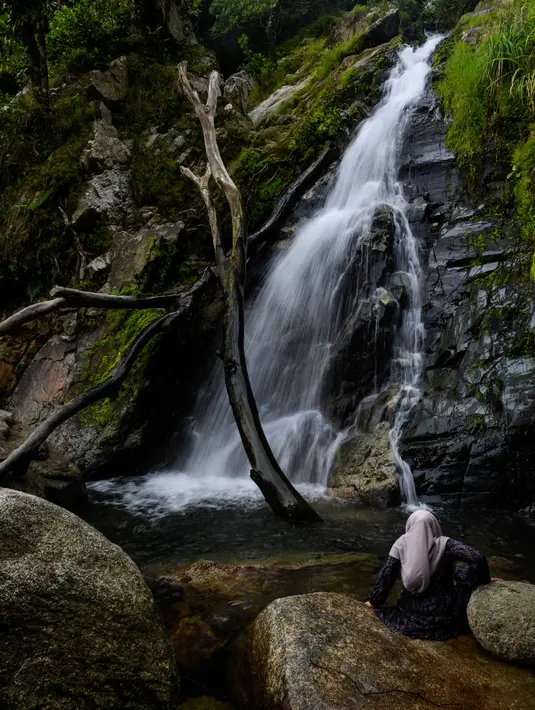 Seorang perempuan menikmati air terjun di Samadua, Provinsi Aceh pada 9 Juli 2020. Aceh punya banyak destinasi wisata alam  mempesona yang patut dikunjungi. (Photo by CHAIDEER MAHYUDDIN / AFP)
