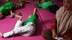 Seorang anak penderita cerebral palsy berbaring di samping ibunya saat berkumpul bersama keluarga untuk memperingati Hari Cerebral Palsy Sedunia di pusat fisioterapi Yayasan Sahabat Difabel di Banda Aceh (6/10/2021). (AFP/Chaideer Mahyuddin)