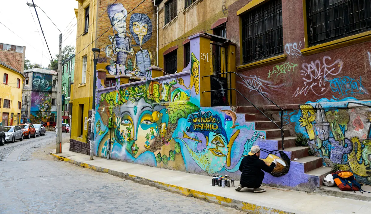 Seniman Sammy Espinosa menyelesaikan mural jalanan di Valparaiso, Chile, 9 April 2019. Valparaiso menjadi galeri seni terbuka raksasa. (Martin BERNETTI/AFP)