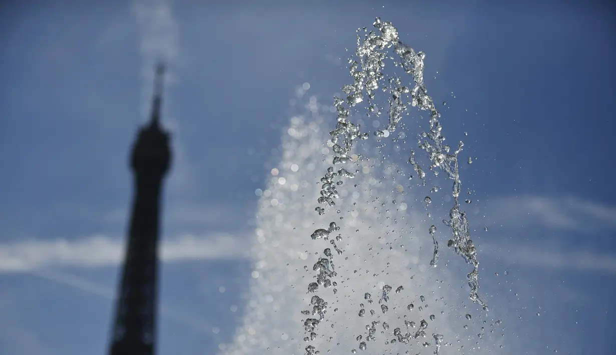 Sebuah foto menunjukkan semburan air di dekat air mancur Trocadero dekat Menara Eiffel, di tengah suhu tinggi di Paris, Kamis (16/6/2022). Prancis akan mengalami suhu yang memecahkan rekor mendekati 40 derajat Celcius pada Juni, karena gelombang panas dini yang diperkirakan akan melanda sebagian besar negara itu.
(JULIEN DE ROSA / AFP)