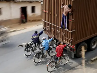 Para Pengendara sepeda menumpang di belakang sebuah truk di luar ibukota Bujumbura, Burundi, (19/7/2015). Untuk menjual pisang Setiap hari puluhan pengendara sepeda dari Bugarama menuruni jalanan bukit sepanjang 45 kilometer. (REUTERS/Mike Hutchings)