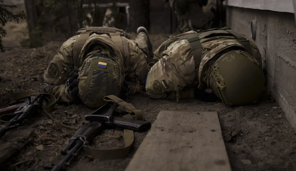 Tentara Ukraina berlindung dari tembakan artileri yang masuk di Irpin, pinggiran Kyiv, Minggu, 13 Maret 2022. Tepat pada hari ini, Kamis, 24 Maret 2022, invasi Rusia ke Ukraina sudah terhitung genap satu bulan penuh. (AP Photo/Felipe Dana)
