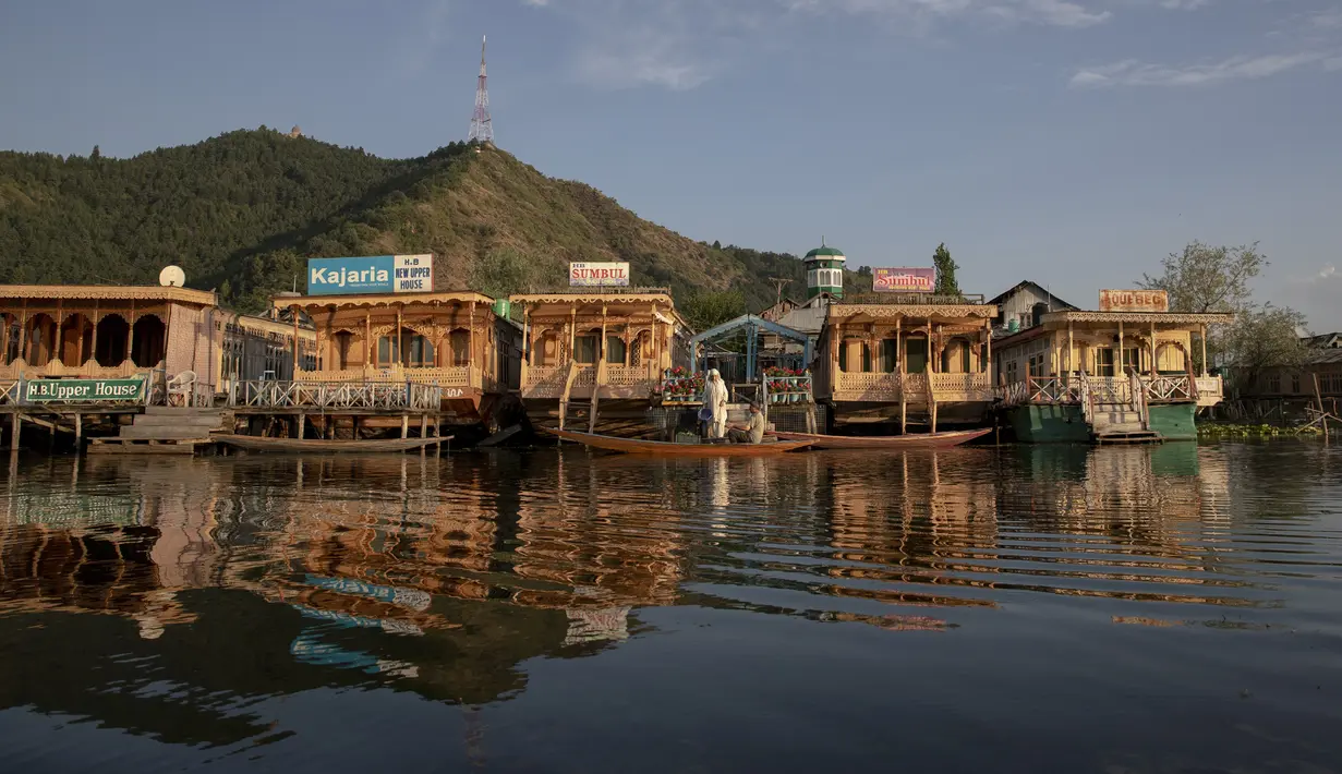 Seorang wanita membeli sayuran dari penjual di shikara atau gondola tradisional di Danau Dal, Srinagar, Kashmir, India, Rabu (22/7/2020). Danau Dal terkenal dengan airnya yang jernih dan tenang. (AP Photo/Dar Yasin)