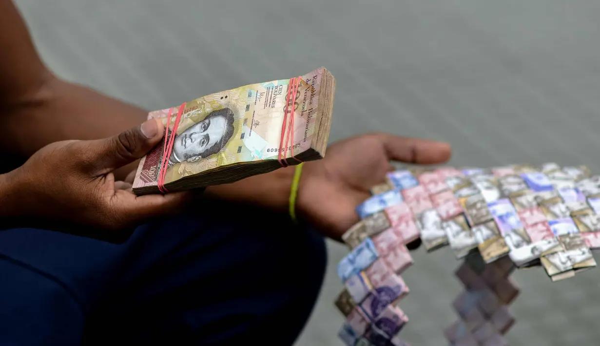 Wilmer Rojas (25) menunjukkan lembaran mata uang Bolivar di Caracas, Venezuela, 30 Januari 2018. Dengan menggunakan jarum dan benang, Rojas menyulap lembaran Bolivar menjadi dompet hingga tas. (AFP Photo/Federico Parra)