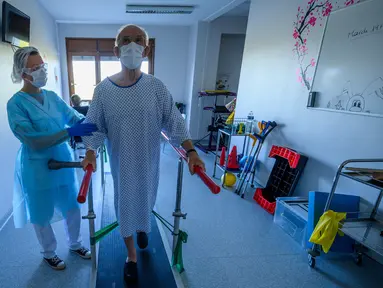 Fisioterapis merawat pasien yang sedang menjalani proses rehabilitasi setelah sembuh dari infeksi virus corona COVID-19 di sebuah rumah sakit di Illkirch-Graffenstaden, Prancis, Selasa (14/4/2020). Prancis memperpanjang lockdown karena dinilai ampuh menahan kasus baru COVID-19. (PATRICK HERTZOG/AFP)