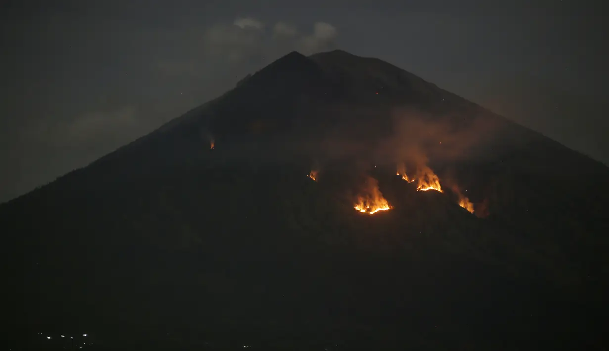 Api membakar hutan lereng Gunung Agung setelah terjadinya lontaran batu pijar dari kawah terlihat dari Karangasem, Bali, Selasa (3/7). Lontaran lava pijar pun teramati keluar kawah dengan jarak mencapai 2 ribu meter. (AP/Firdia Lisnawati)