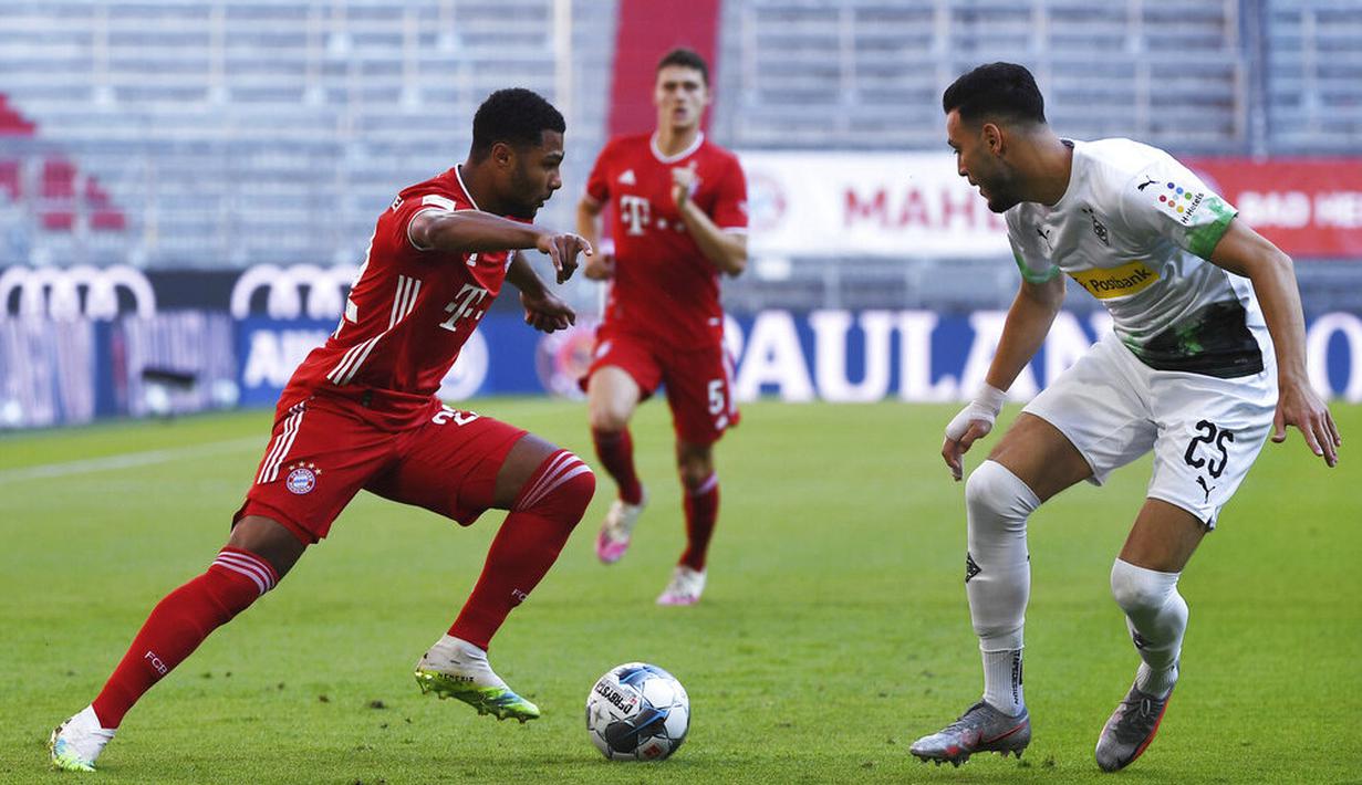 Pemain Bayern Munchen, Serge Gnabry, berusaha melewati pemain Borussia Moenchengladbach, Ramy Bensebaini, pada laga Bundesliga di Allianz Arena, Minggu (14/6/2020). Bayern Munchen menang 2-1 atas Borussia Moenchengladbach. (AP/Matthias Balk)