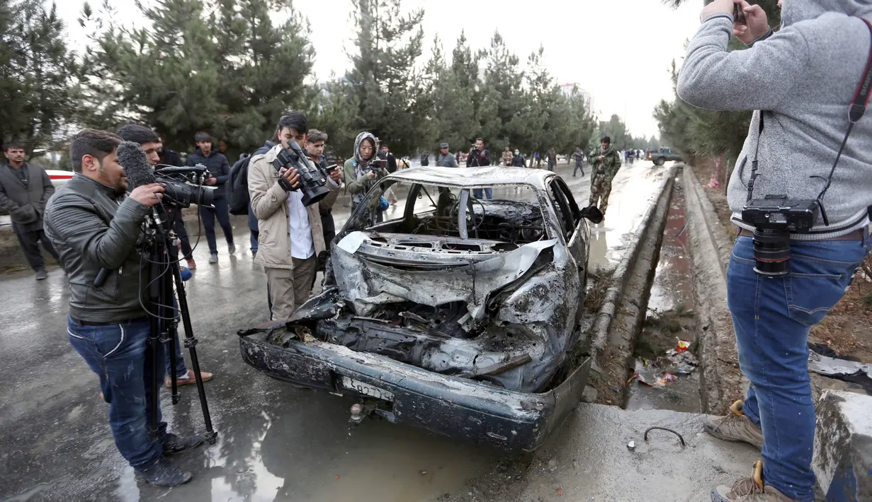 Sejumlah awak media mengambil gambar mobil yang hancur akibat ledakan bom bunuh diri di Kabul, Afghanistan (15/11). Akibat bom bunuh diri ini sedikitnya sembilan orang tewas dan sebagian lainnya mengalami luka-luka. (AP Photo/Rahmat Gul)