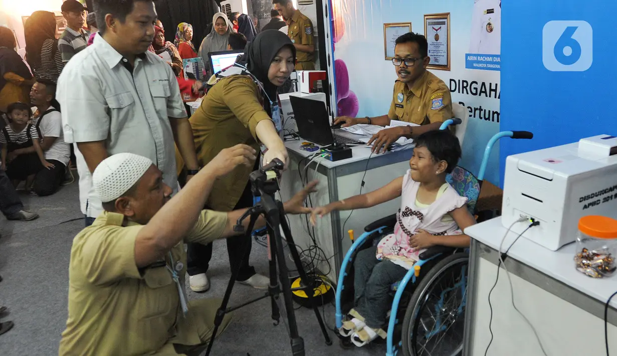 Petugas Disdukcapil Kota Tangerang Selatan melakukan pemotretan kartu identitas anak (KIA) untuk anak penderita Spina Bifida di  Lapangan Skadron 21 Sena Penerbad, Tangerang Selatan, Banten (25/11/2019). Sekitar 500 anak melakukan pembuatan KIA secara gratis. (merdeka.com/Arie Basuki)