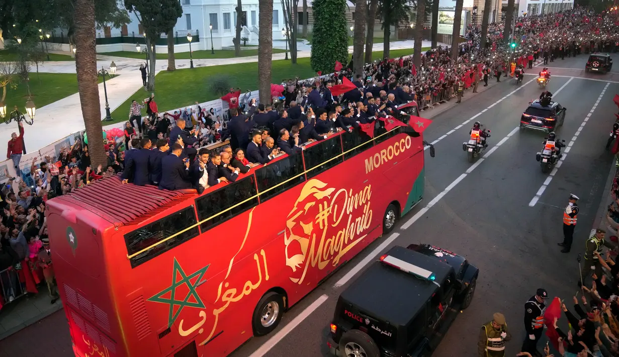 <p>Para pemain timnas Maroko melakukan selebrasi di atas bus dan melambaikan tangan ke publik saat parade di Rabat , Maroko, 20 Desember 2022. Timnas Maroko mendapat sambutan hangat di negaranya setelah berhasil meraih juara keempat Piala Dunia 2022. (AP Photo/Mosa'ab Elshamy)</p>