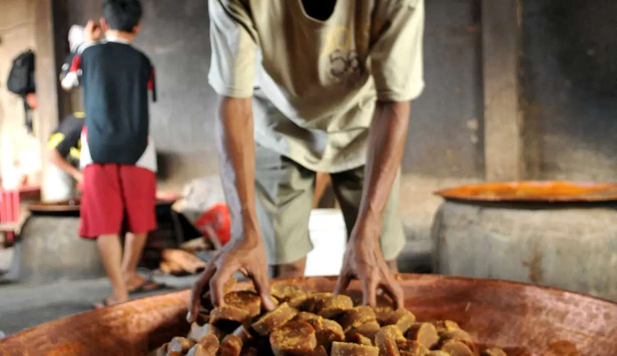 Pekerja memasukkan gula aren ke dalam kuali di kawasan Pasar Minggu, Jakarta, Kamis (23/6). Harga Dodol Betawi rasa ketan putih dan ketan item dijual mulai dari harga Rp50 ribu per besek.  (Liputan6.com/Gempur M Surya)