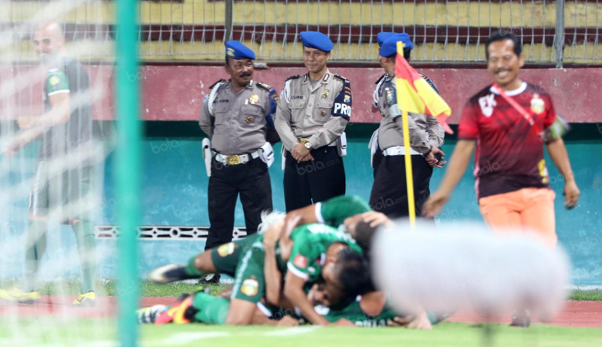 Polisi tersenyum saat melihat para pemain Bhayangkara Surabaya United merayakan gol ke gawang Persib Bandung pada lanjutan Torabika SC 2016 di Stadion Gelora Delta Sidoarjo, Sabtu (11/6/2016). (Bola.com/Nicklas Hanoatubun)