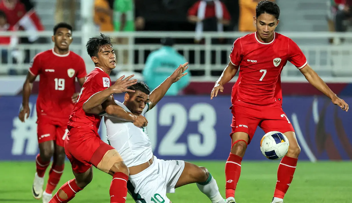 <p>Pemain Timnas Indonesia U-23, Pratama Arhan (kiri) berebut bola dengan pemain Irak U-23, Nihad Mohammed pada laga perebutan tempat ketiga Piala Asia U-23 2024 di Abdullah bin Khalifa Stadium, Doha, Qatar, Kamis (2/5/2024). (AFP/Karim Jaafar)</p>