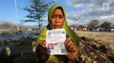 Seorang ibu bernama Lita, menunjukkan foto anaknya, Nanang Kosim (20) yang belum ditemukan pascagempa dan tsunami Palu di Pantai Talise, Sulawesi Tengah, Senin (8/10). Nanang diduga masih tertimbun di dalam tanah saat tsunami. (Liputan6.com/Fery Pradolo)