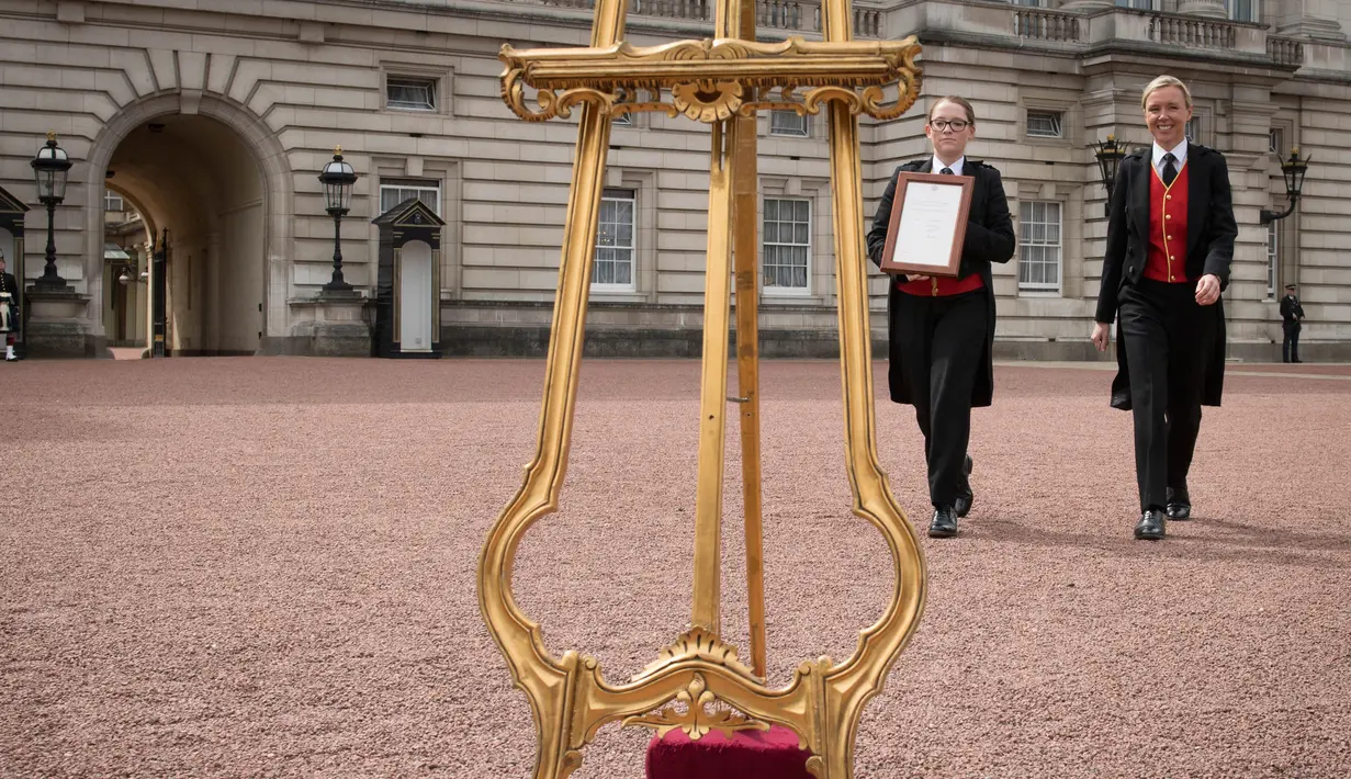 Senior footman Olivia Smith dan Heather McDonald saat akan memajang pengumuman kelahiran bayi baru kerajaan di halaman depan Istana Buckingham, London, Inggris, Senin (23/4). Anak ketiga Kate Middleton berjenis kelamin laki-laki. (Pool Photo via AP)