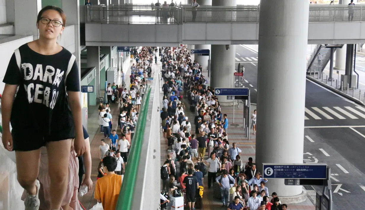 Penumpang yang terdampar antre menunggu bus khusus di Bandara Internasional Kansai menyusul topan Jebi yang menghantam Jepang, Rabu (5/9). Topan jebi telah merusak jembatan yang menghubungkan Bandara Kansai dengan daratan utama Osaka. (Kyodo News via AP)