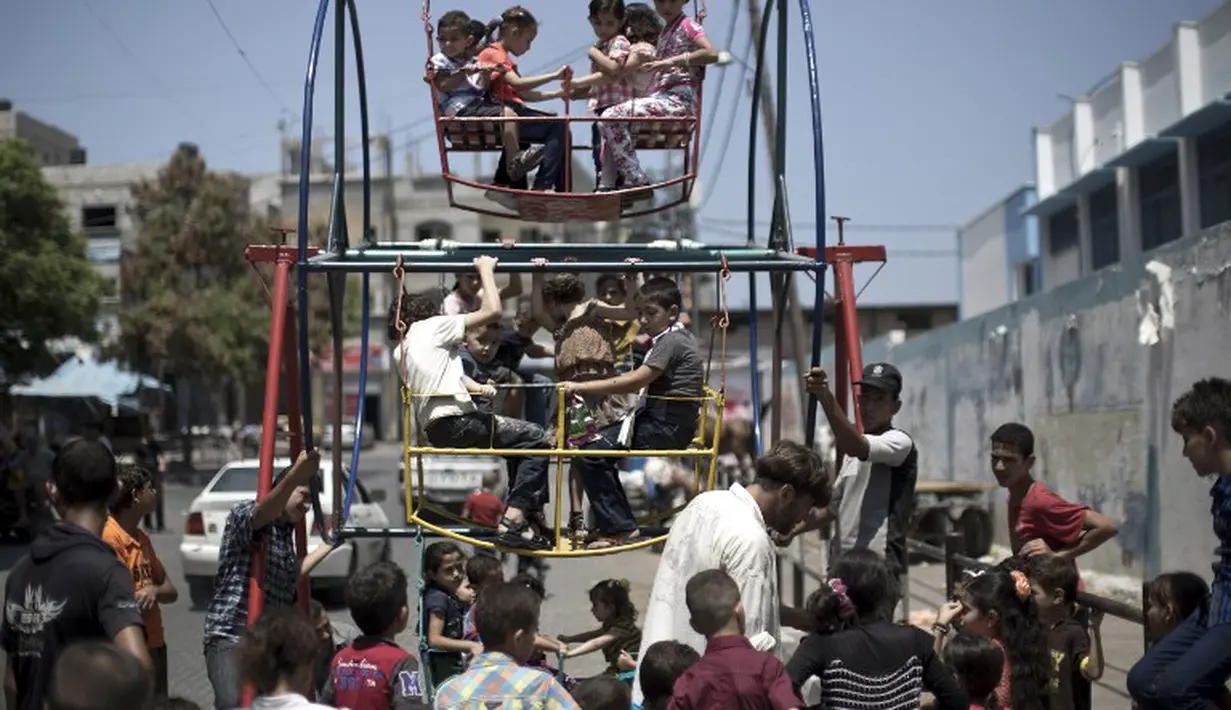 Sejumlah anak-anak Palestina tengah asyik bermain kincir di kamp pengungsi Sekolah PBB di Jabalia, Gaza (28/7/14). (AFP PHOTO/Mahmud HAMS)