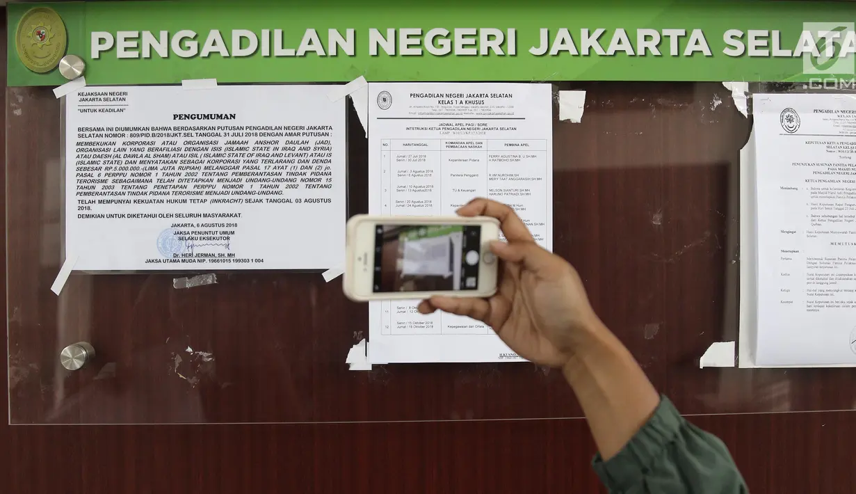 Pengunjung mengambil gambar pengumuman pembekuan Jamaah Ansharut Daulah (JAD) di salah satu papan pengumuman PN Jakarta Selatan, Senin (6/8). Jaksa melaksanakan eksekusi putusan pembekuan JAD sebagai organisasi terlarang. (Liputan6.com/Herman Zakharia)