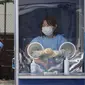 Seorang pekerja medis memegang kipas angin portabel selama panas terik sementara petugas polisi menjalani tes COVID-19 di klinik darurat di Badan Kepolisian Metropolitan Seoul di Seoul, Korea Selatan, Rabu, (19/8/2020). (AP Photo / Ahn Young -joon)