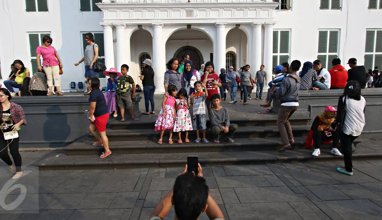 Warga berfoto di kawasan Kota Tua, Jakarta, Minggu (8/5). Meskipun libur panjang akan berakhir, Warga tetap memadati kawasan wisata Kota Tua. (Liputan6.com/Immanuel Antonius)