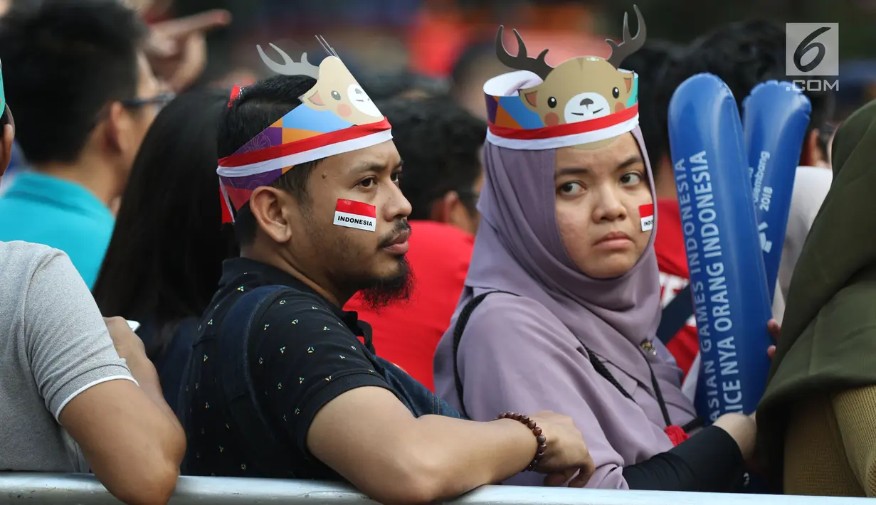 Calon penonton menggunakan hiasan saat antre masuk menyaksikan laga final bulu tangkis beregu putra di Istora Senayan Jakarta, Rabu (22/8). Laga final bulu tangkis beregu putra mempertemukan Indonesia melawan China. (Liputan6.com/Helmi Fithriansyah)