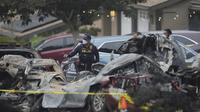 Pihak berwenang memeriksa lokasi pesawat jatuh di kawasan permukiman San Diego, AS yang menyebabkan beberapa rumah terbakar Kamis dini hari, 22 Mei 2025. (AP/Gregory Bull)