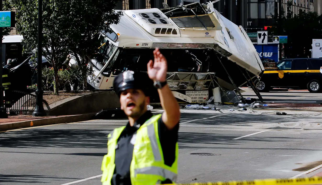 Petugas berjaga di garis polisi di lokasi kejadian tabrakan dua bus di Newark, New Jersey (19/08) waktu setempat. Seorang pengemudi bus New Jersey Transit tewas dan 19 orang dirawat di rumah sakit. (REUTERS/Eduardo Munoz)