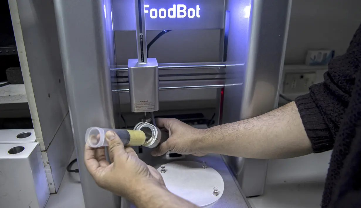 Mahasiswa teknik makanan Marcelo Beltran menunjukkan cara memasukkan makanan ke dalam printer 3D di Laboratorium Universitas Chile, Santiago, Chile, 17 Juni 2022. Makanan cetak 3D berusaha merevolusi pasar makanan, terutama ditujukan untuk anak-anak di Chile. (Martin BERNETTI/AFP)