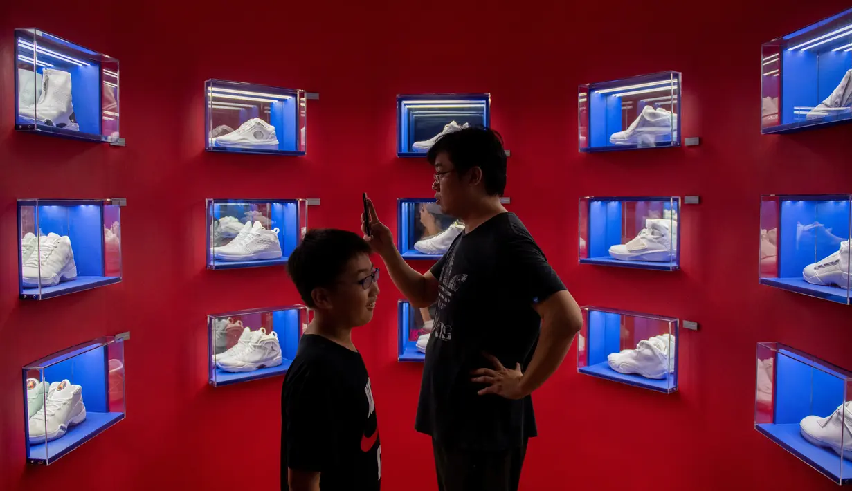 Pengunjung melihat sepatu Air Jordan yang dipamerkan dalam pameran NBA (National Basketball Association) di Beijing, China, Senin (19/8/2019). (NICOLAS ASFOURI/AFP)