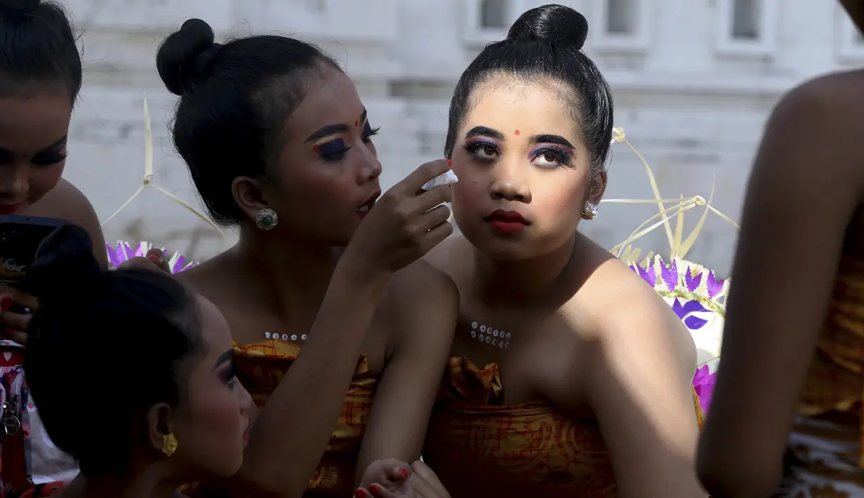 Penari wanita muda mempersiapkan diri untuk tampil pada perayaan Hari Raya Kuningan di Pura Sakenan, Bali, Sabtu (18/6/2022). Kuningan menandai hari terakhir perayaan Galungan, salah satu upacara keagamaan terbesar umat Hindu di Bali. (AP Photo/Firdia Lisnawati)