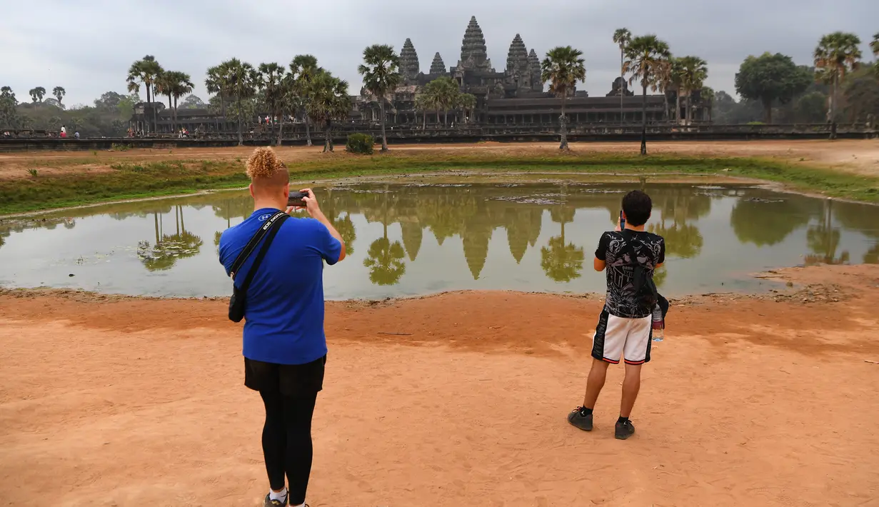 Wisatawan mengambil gambar di Kuil Angkor Wat, Provinsi Siem Reap, Kamboja, Kamis (5/3/2020). Menurut World Travel and Tourism Council, wabah virus corona (COVID-19) membuat sektor pariwisata dunia kehilangan USD 22 miliar. (TANG CHHIN Sothy/AFP)