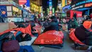 Orang-orang menghabiskan malam dengan tidur di area terbuka dalam acara World's Big Sleep Out di Times Square, New York, 7 Desember 2019. Aksi di beberapa kota besar dunia ini sebagai bagian dari upaya penggalangan dana untuk membantu para tunawisma di banyak negara. (Charles Sykes/Invision/AP)