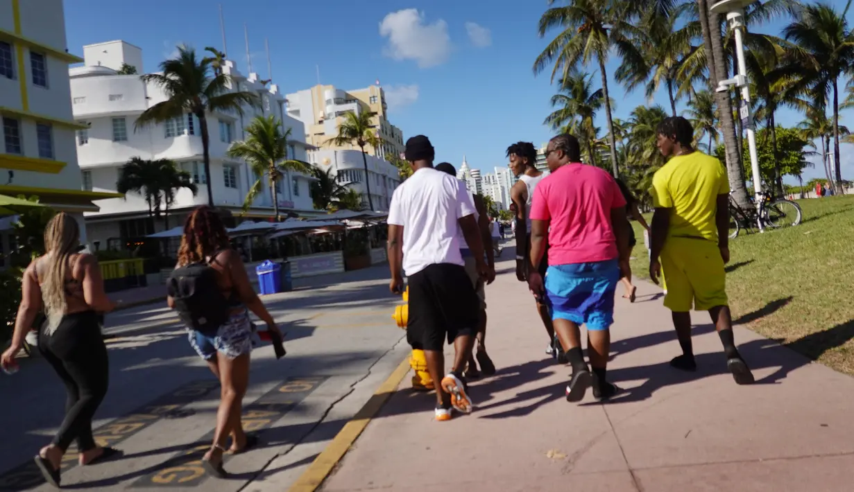 Orang-orang berjalan di sepanjang Ocean Drive di Miami Beach, Florida, Selasa (16/3/2021). Mahasiswa telah tiba di daerah Florida Selatan untuk liburan musim semi. Para pejabat kota prihatin dengan kerumunan liburan musim semi saat pandemi COVID-19 terus berlanjut. (Joe Raedle/Getty Images/AFP)