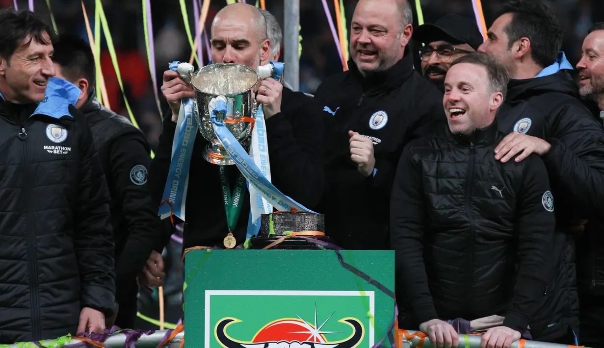 Manajer Manchester City, Pep Guardiola, mencium trofi Piala Liga Inggris setelah mengalahkan Aston Villa pada laga final di Stadion Wembley, London, Minggu (1/3/2020). Manchester City memastikan trofi Piala Liga Inggris ketiga secara beruntun setelah menang 2-1 atas Aston Villa. (AP/Ian Walton)