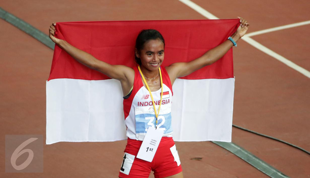Atlet putri Indonesia, Triyaningsih membentangkan sang Merah Putih saat melakukan perayaan kemenangannya di nomor 10.000 M di National Stadium Singapura, (11/6/2015). Triyaningsih mencatatkan waktu 33 menit 44,53 detik. (Liputan6.com/Helmi Fithriansyah)