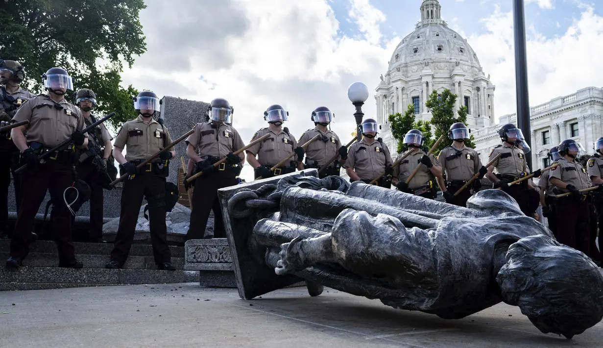 Polisi berjaga saat sekelompok massa merobohkan patung Christopher Columbus di Minnesota State Capitol, St. Paul, Minnesota, Amerika Serikat, Rabu (10/6/2020). Patung Christopher Columbus jadi amukan massa setelah kematian George Floyd. (Evan Frost/Minnesota Public Radio via AP)