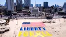 Foto udara yang diambil pada Jumat 4 Juli 2025 menunjukkan instalasi pasir yang menggambarkan bendera Amerika Serikat (AS) dan slogan “Liberty for All” atau Kebebasan untuk Semua di salah satu pantai di luar kantor cabang Kedutaan Besar (Kedubes) Amerika Serikat (AS) di Tel Aviv, Israel. (Jack GUEZ/AFP)