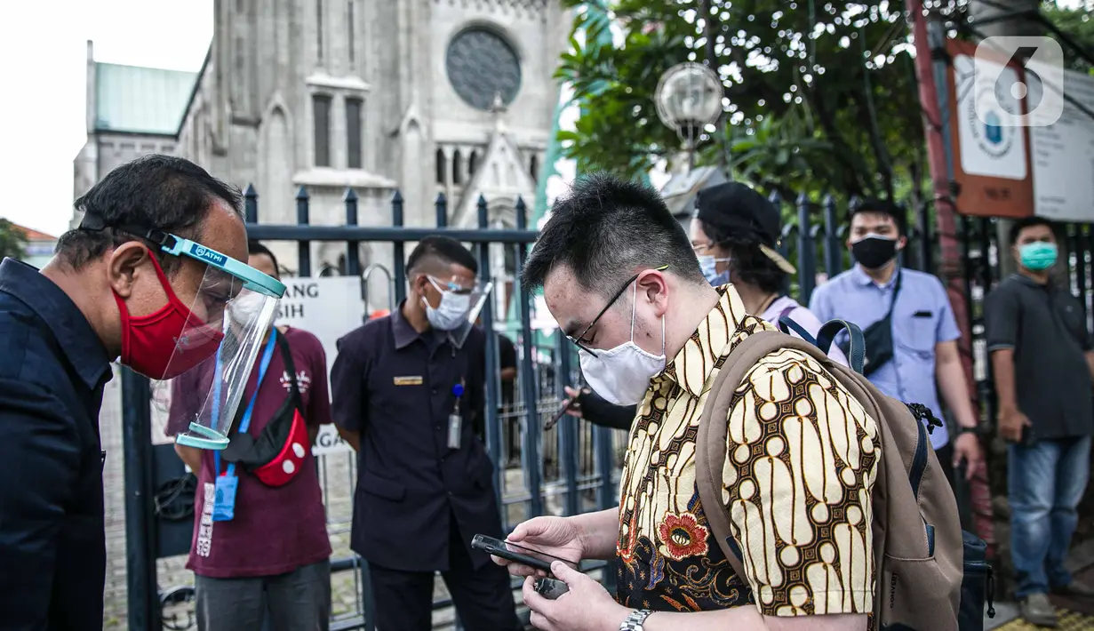 Seorang Jemaat memperlihatkan bukti pendaftaran untuk mengikuti ibadah di Gereja Katedral, Jakarta, Kamis (24/12/2020). 200 umat berada di dalam Gereja Katedral dan 109 umat berada di Plaza Maria. (Liputan6.com/Faizal Fanani)