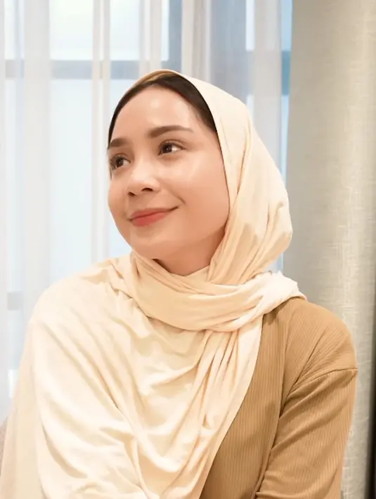 Sama halnya saat bikin konten review di mana Nagita Slavina tetap pakai kerudung. Ia memakai pleated dress cokelat berpadu dengan kerudung berwarna krem. [@raffinagita1717]