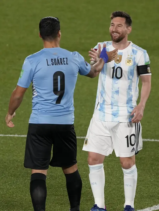 Penyerang Argentina Lionel Messi dan penyerang Uruguay Luis Suarez berjabat tangan sebelum laga Kualifikasi Piala Dunia 2022 Zona Amerika Selatan di Monumental stadium, Senin (11/10/2021) WIB. Duel ini menjadi momen reuni dua mantan pemain Barcelona, Messi dan Suarez. (AP Photo/Natacha Pisarenko)
