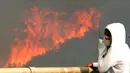 Seorang warga menutup hidungnya saat kebakaran besar yang melanda kota pantai Valparaiso di Chile, Senin (2/1). Puluhan petugas pemadam dari kota Valparaiso dan kota-kota sekitarnya dikerahkan untuk memadamkan kebakaran itu. (REUTERS/Rodrigo Garrido)