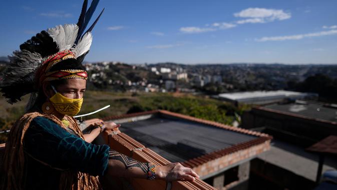 Angoho, pemimpin kelompok etnis Pataxo Hahahae, mengenakan masker di Vila Vitoria favela di pinggiran Belo Horizonte, negara bagian Minas Gerais, Brasil (8/7/2020). Angoho dan saudara-saudaranya diusir karena krisis air yang disebabkan penyebaran aforestasi kayu putih. (AFP/Douglas Magno)